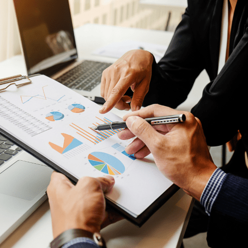 Two professionals reviewing charts and graphs on a tablet and paper documents, representing software development process monitoring and validation by PureLogics.